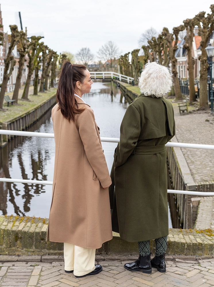 Coach verlies noord, verlies, Fotografie van Coach Ingrid die met een oudere dame praat op een brug in Sloten tijdens een coachingssessie in de buitenlucht